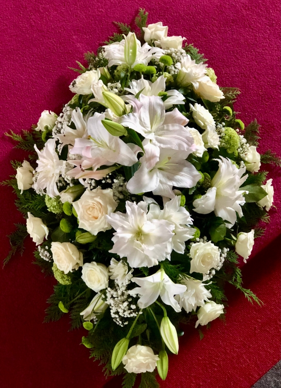 A traditional lily and rose coffin spray